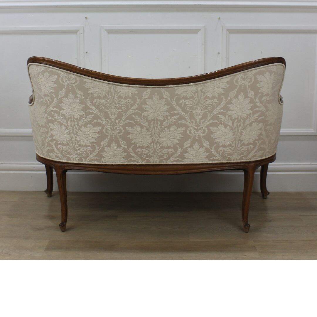 settee with carved curvy frame and beige fabric